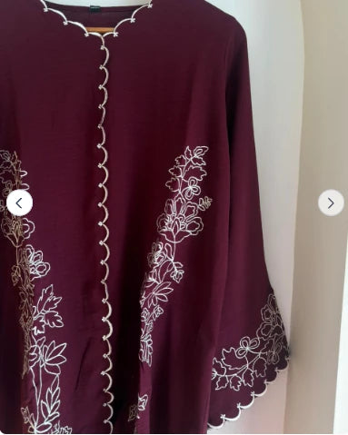 Close-up of floral embroidery and scalloped trim on maroon microcrepe one piece
