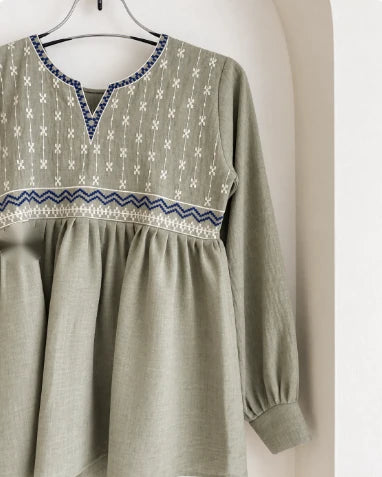Close-up of white cross-stitch and blue zigzag embroidery on sage green cotton kurti
