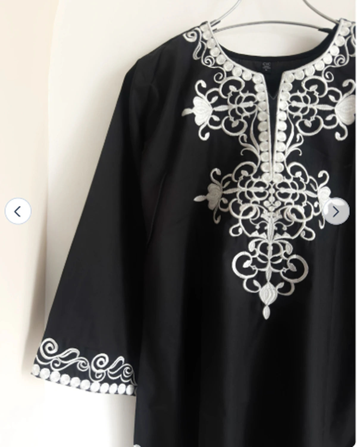 Close-up of white embroidery detail on black cotton tunic neckline and sleeve