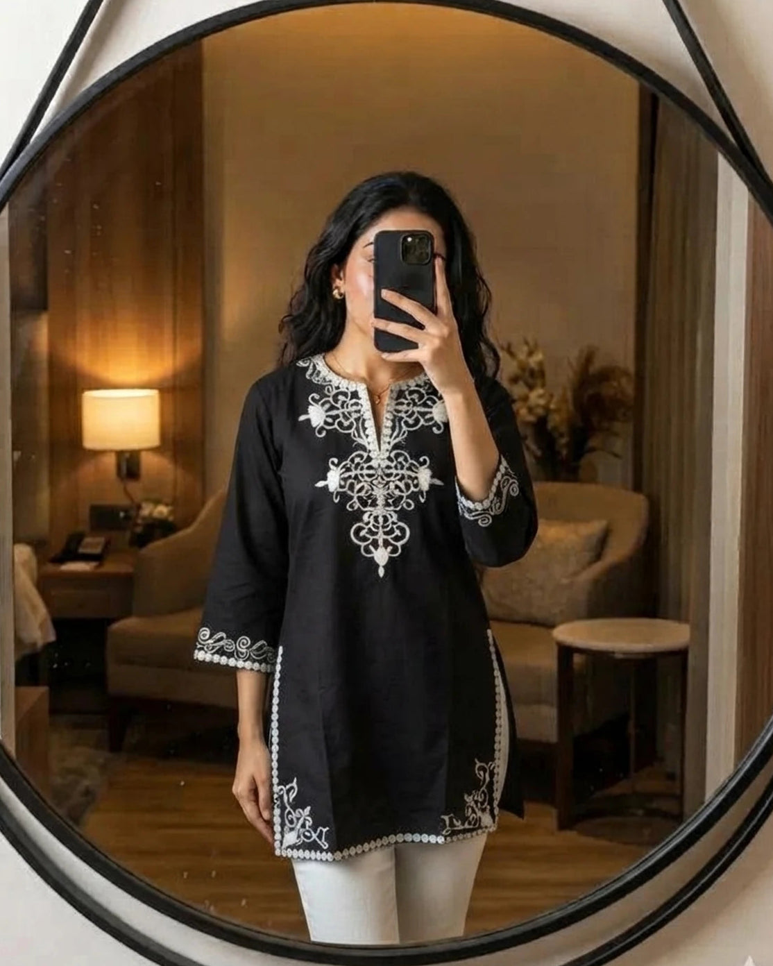 Woman wearing black embroidered cotton tunic, front mirror pose
