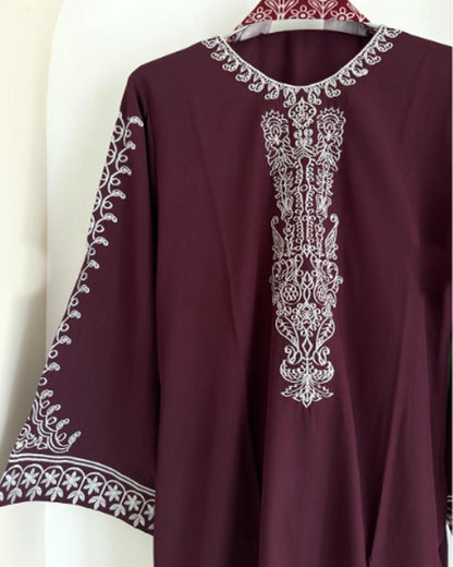 Close-up of white thread embroidery on maroon kurti neckline and sleeve