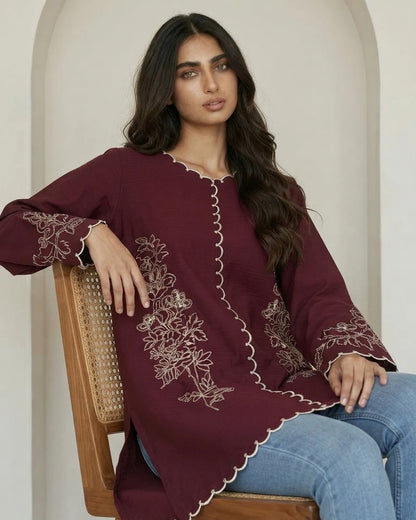 Woman wearing maroon floral embroidered microcrepe one piece, seated pose