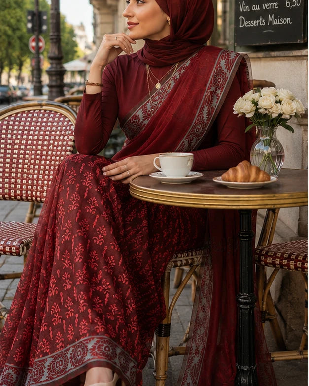 Woman in maroon block print saree with hijab seated at Paris café table