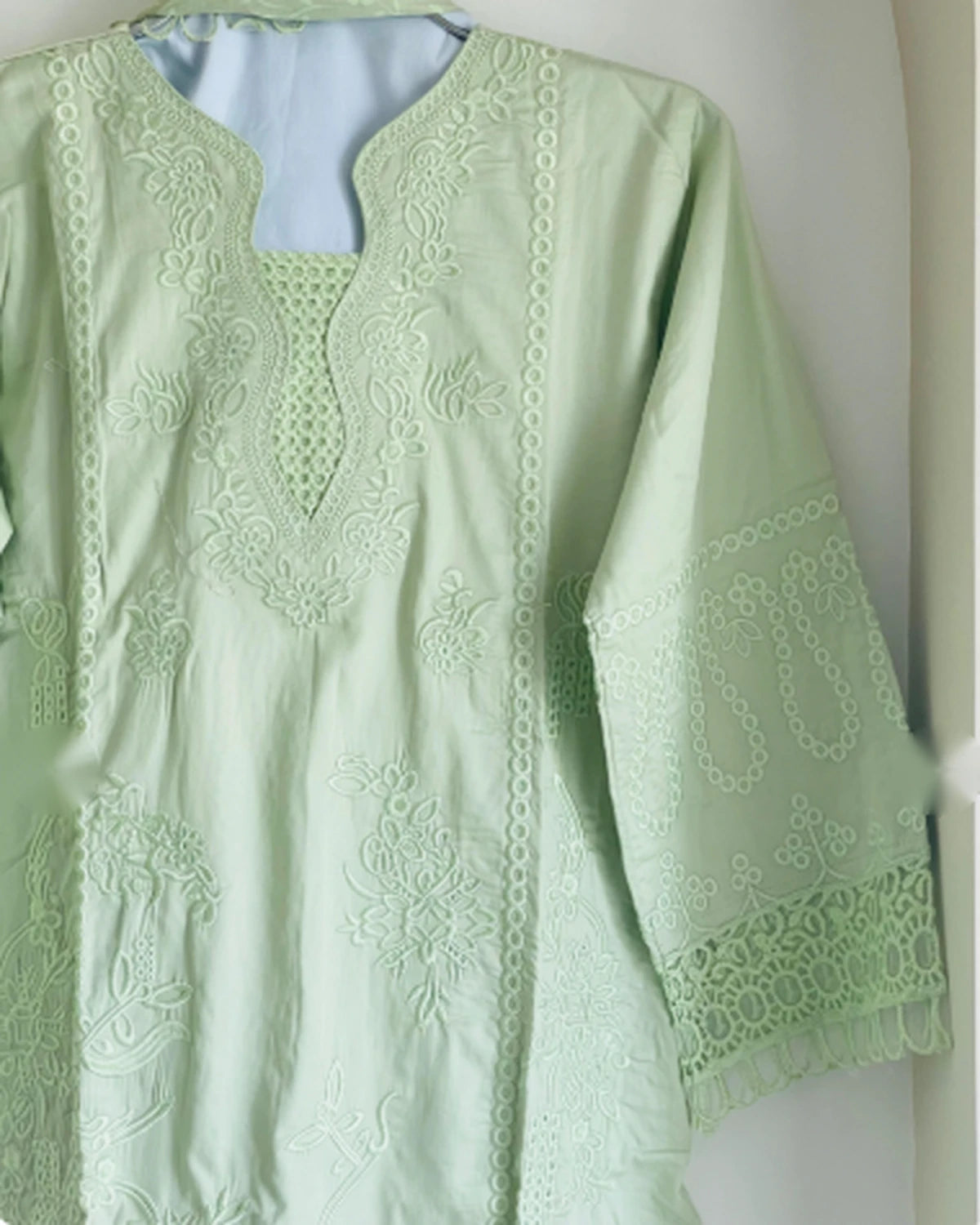 Close-up of thread embroidery and lace detail on mint green kameez neckline