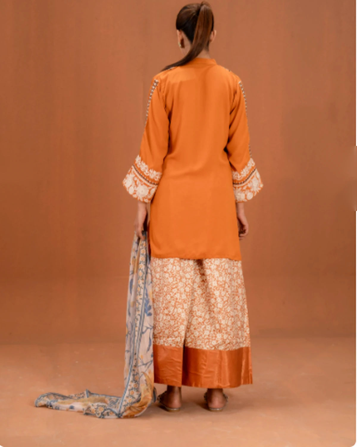 Woman wearing orange embroidered 3pc suit, back view showing sleeve embroidery
