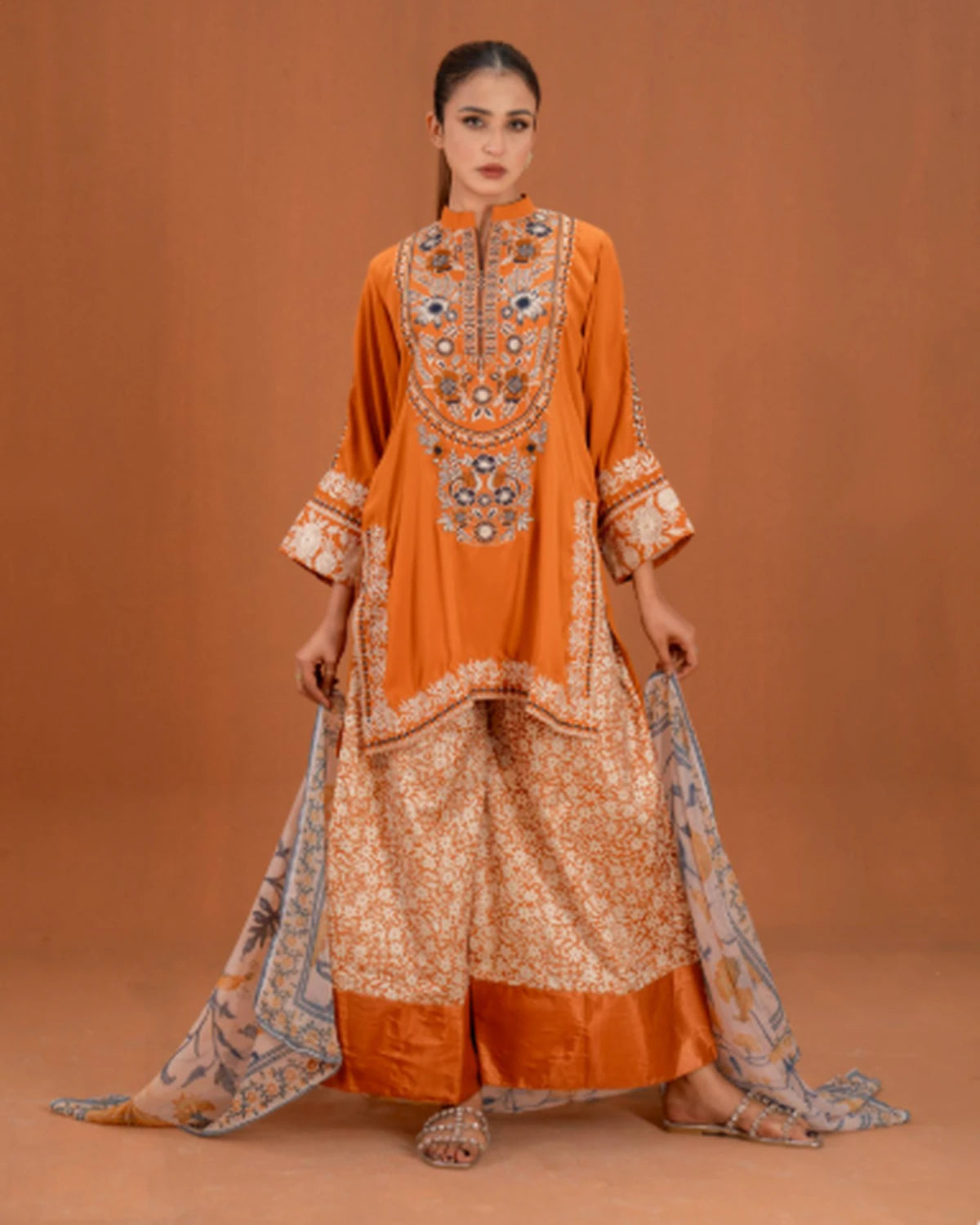 Woman wearing orange embroidered 3pc suit with printed palazzo and dupatta, front pose