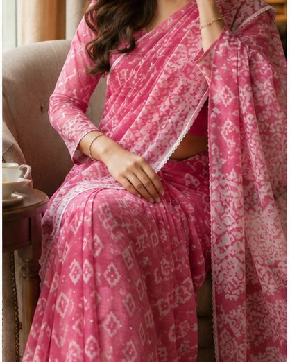 Woman in pink batik print saree seated in armchair, portrait