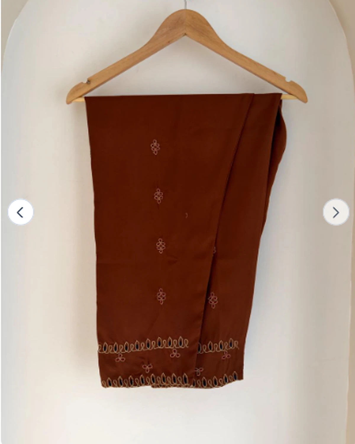 Rust brown embroidered pants on hanger with matching hem detail