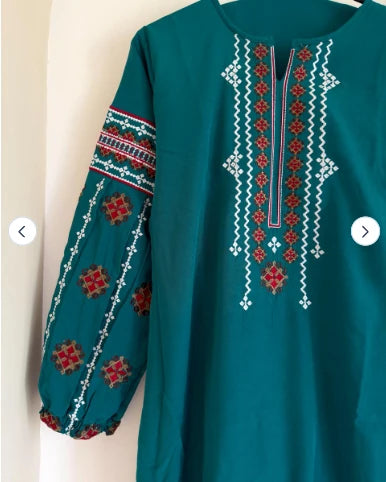 Close-up of folk cross-stitch embroidery on teal cotton top sleeve and neckline